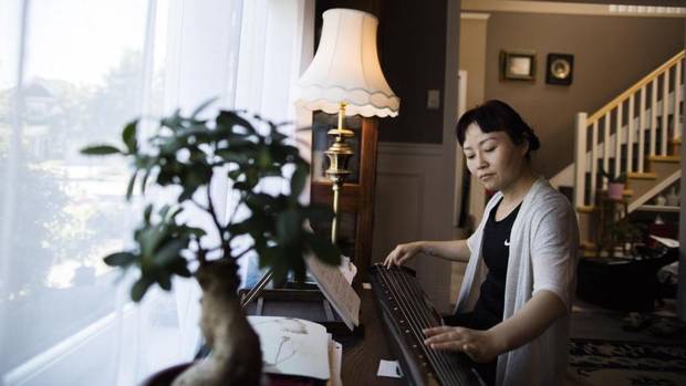 Anita He plays the guqin, a traditional Chinese instrument, at her home in Richmond.