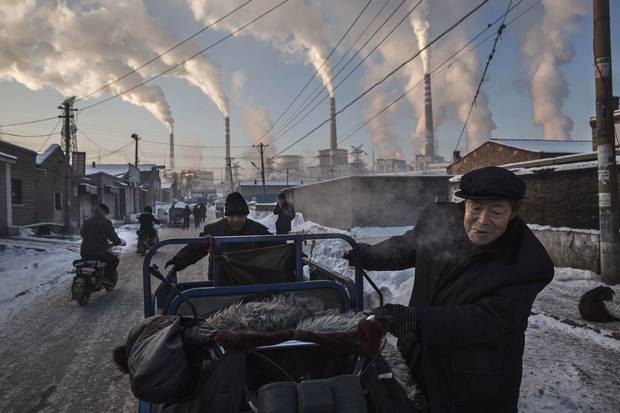 Nov. 26, 2015: Smoke billows from stacks as Chinese men pull a tricycle in a neighborhood next to a coal-fired power plant in Shanxi, China.