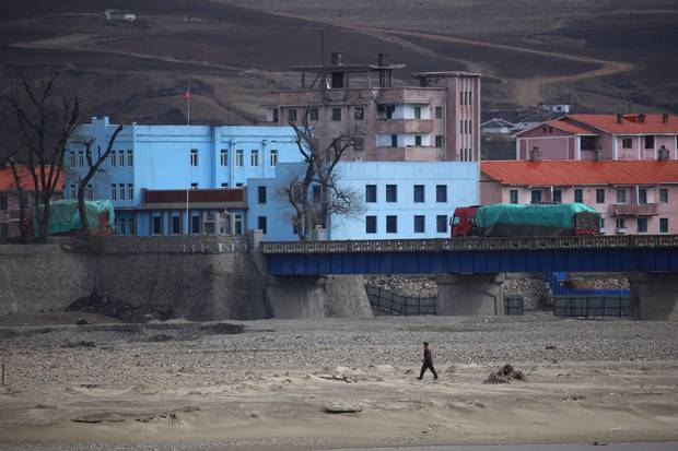 A uniformed North Korean man walks along the North Korean side of the Tumen River, which separates the isolated regime from China. Despite recent tensions, trucks are still crossing the border.
