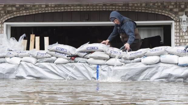 A man fixes a hose connected to a pump at his flooded house on Ile Bizard, Que., near Montreal, Monday, May 8, 2017.