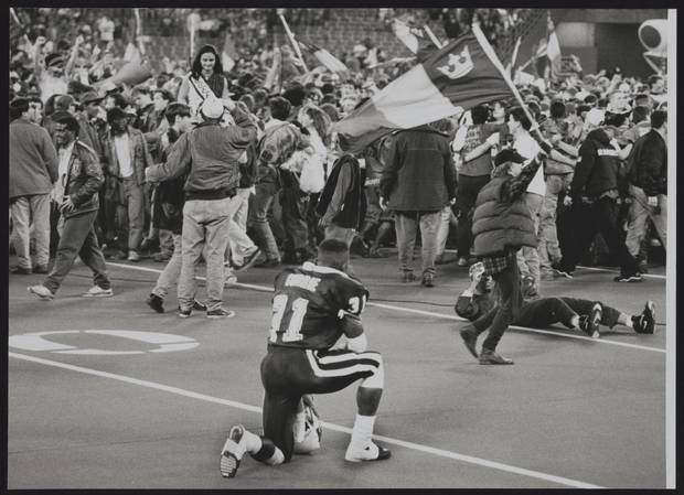 A dejected St. Mary's Huskies player looks on as the opposing team's fans take to the field in celebration.