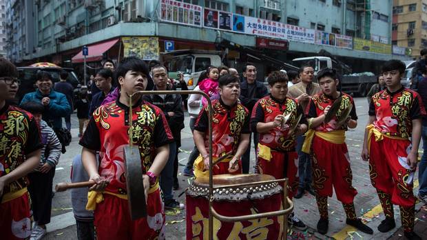 People watch as a lion dance team performs on a street during Lunar New Year celebrations in Hong Kong on February 12, 2016.