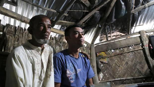 Abul Taher sits with his son Muhammad Selim, who left Bangladesh earlier this year as part of a tide of people seeking better prospects in Malaysia.