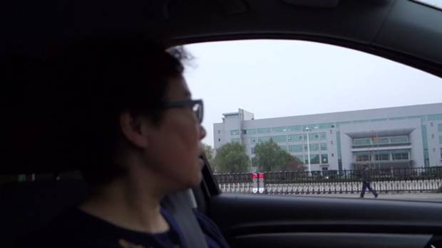 Jean Zou drives past the cigarette factory where her husband worked.