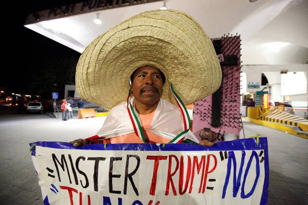Martin Macias holds a placard against U.S. Republican presidential nominee Donald Trump while standing at Paso del Norte international border crossing bridge in Ciudad Juarez, Mexico, on Nov. 8, 2016.