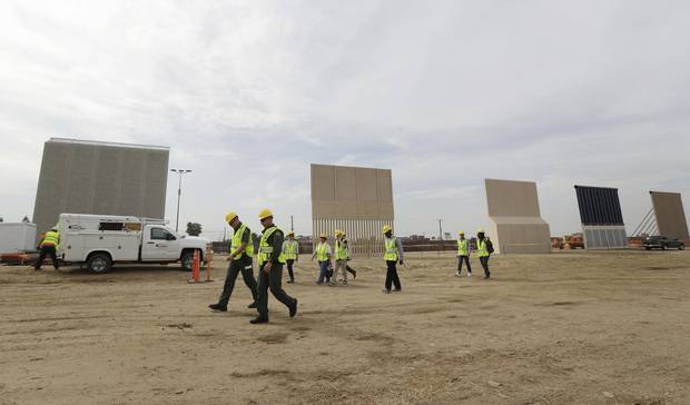 People pass wall prototypes near the border with Tijuana, Mexico, Thursday, Oct. 19, 2017, in San Diego.