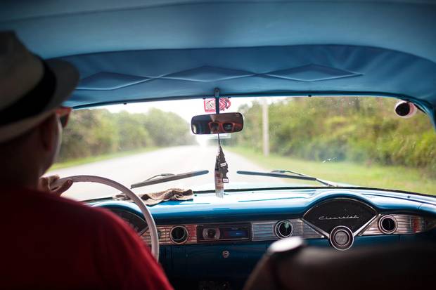A view of the highway outside of Havana. The Cuban government allows individual Cubans to work privately driving restored antique cars for tourists. Yadir, pictured here, and a driver hired by the photographer had been driving this 1956 Chevy privately for three years.