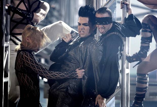 American Idol alum Adam Lambert (right) brought a millennial sense of glam to his performances, including a sparkling suit worn during his notorious performance at the American Music Awards in 2009, though he now sports a more toned down look.