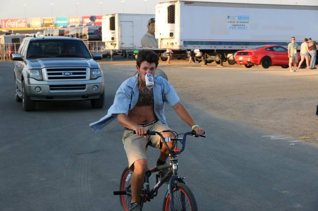 A fan drinks beer while biking around the infield during the Coca-Cola 600 at Charlotte Motor Speedway.