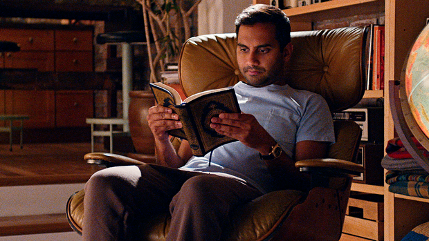 Dev from Netflix's Master of None sits in a classic Eames chair in his apartment. 