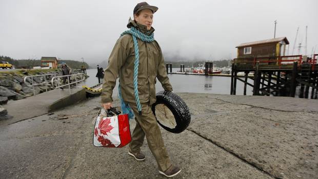 Connor Paone cleans up debris, including a discarded tire, during the Surfrider Pacific Rim Christmas Jingle Cleanup Event along the Tofino harbour shorefront near the 4th Street government dock and marina on December 2, 2016.
