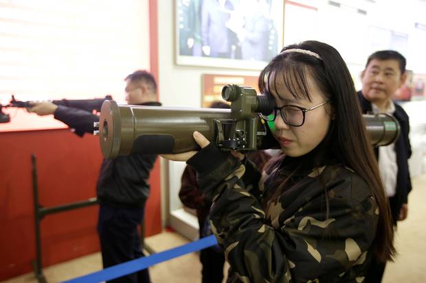 A visitor handles a model of a weapon at a military simulator area.