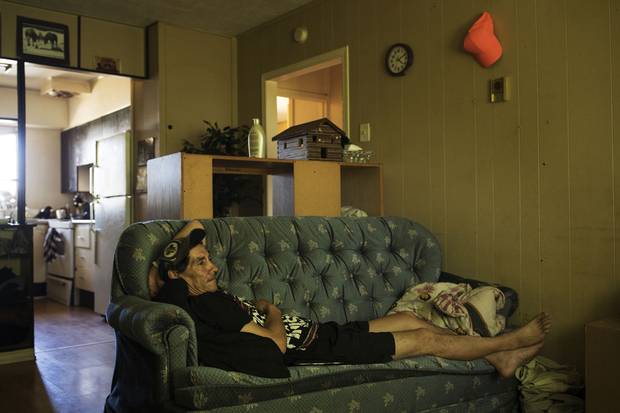 Marleah’s father, James Trout, watches television inside their two-bedroom home. Mr. Trout sleeps on the couch so Marleah and her brother can have their own rooms.