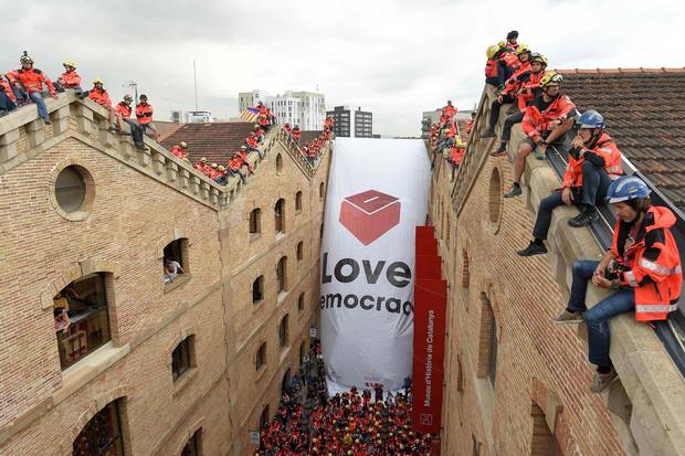 Catalan firefighters unfold a large banner with a ballot box and reading 