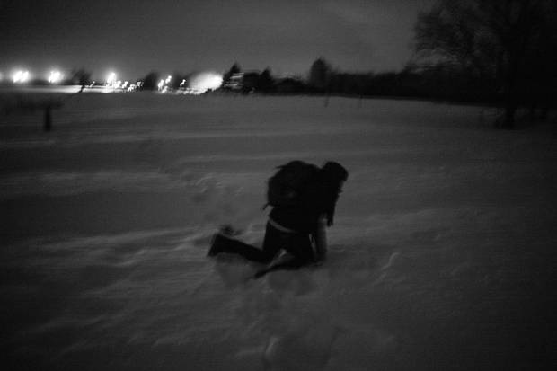 An exhausted asylum seeker, bogged down by heavy snow, crosses the Canadian border in Noyes.