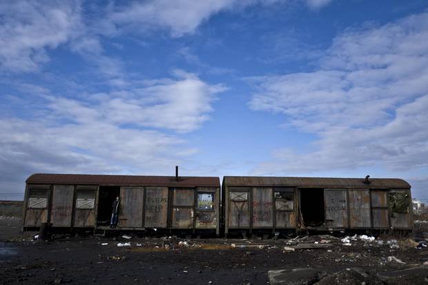 An Afghan refugee youth stands at the doorway of an old train carriage where he and other migrants have taken refuge in Belgrade.