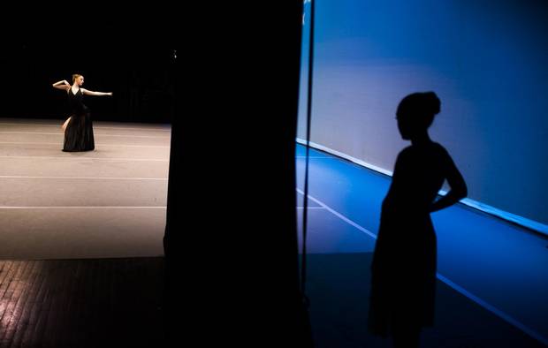 A dancer watches another performer on stage.