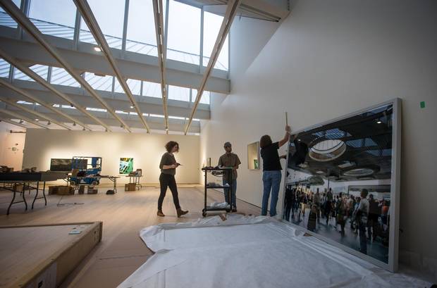 Nomi Stricker, left, Simon Bermeo-Ehmann and gallery manager Diane Edams hang a print of a Thomas Struth photograph taken at Moscow Station in St. Petersburg, in preparation for an auction of major photographic works at the Polygon Gallery.
