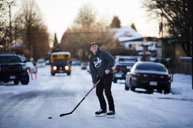 Tyler Mitchell stops for vehicles while playing hockey on the icy street near East 43rd Avenue and St. George Street in Vancouver on Jan. 3, 2017. City of Vancouver crews have fallen behind in maintaining the side streets, turning them into skating rinks.