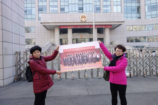 Mr. Wang’s wife, Jean Zou, left, and sister Wang Qin hold the photo they say challenges the case against Mr. Wang. One witness testified that he gave Mr. Wang a bribe in person in October, 2009. But he wasn’t in China then; he was in Romania, where the photo was taken.