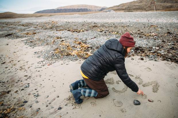 Jena Merkosak writes her grandmother's name in the sand at Dundas Harbour.