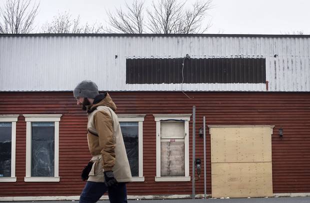A man walks past a boarded-up business in downtown St. John's.