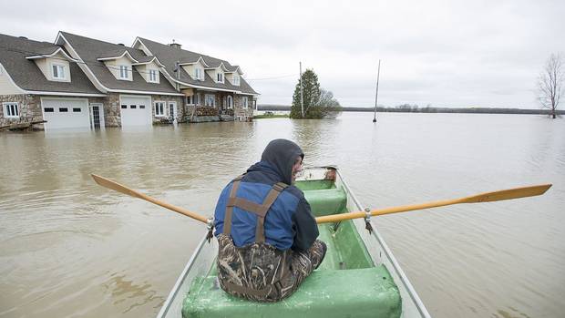 François Lussier rows a small boat along a flooded street in the town of Rigaud, Que., west of Montreal, on May 8, 2017.