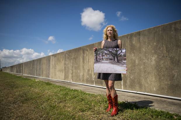Sandy Rosenthal, founder and executive director of Levees.org, stands next to a levee in New Orleans that failed after Hurricane Katrina in 2005. She holds a photo of the home that was destroyed and moved into the middle of the street during the storm surge.