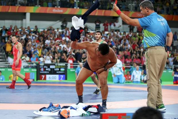 2016 Rio Olympics - Wrestling - Final - Men's Freestyle 65 kg Bronze - Carioca Arena 2 - Rio de Janeiro, Brazil - 21/08/2016. The coach of Mandakhnaran Ganzorig (MGL) of Mongolia takes off his clothes as he protests after the match against Ikhtiyor Navruzov (UZB) of Uzbekistan.