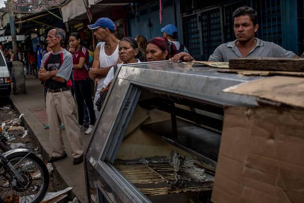 People gather on the street in the El Valle neighbourhood of Caracas after a night of looting in the area saw eight people die.