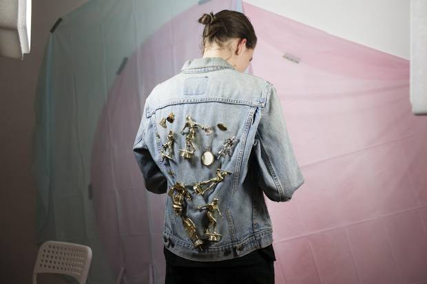 Mx. Gilmer-Osborne wears a denim jacket decorated with their parents’ and their own trophies. ‘I removed the trophy heads and attached them to my oldest denim jacket … my way of carrying my parents with me at all times, while also enjoying the process of destroying symbols of triumph/success/physical ability in order to display them in a queer manner.’ 