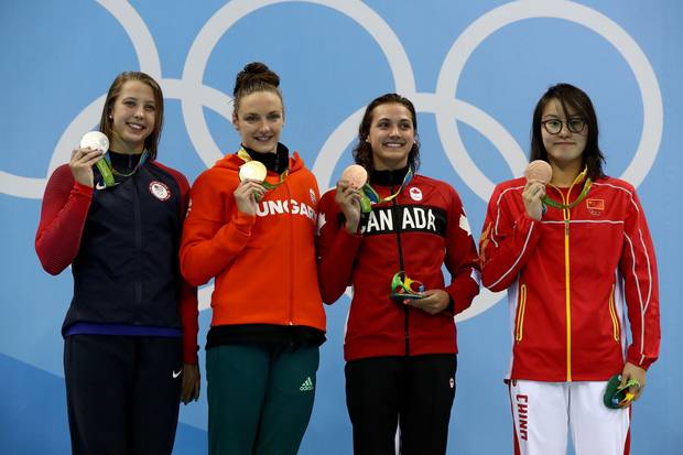 Silver medalist Kathleen Baker of the United States, gold medal medalist Katinka Hosszu of Hungary and bronze medalist's Kylie Masse of Canada and Yuanhui Fu of China pose on the podium during the medal ceremony for the Women's 100m Backstroke Final on Day 3 of the Rio 2016 Olympic Games at the Olympic Aquatics Stadium on August 8, 2016 in Rio de Janeiro, Brazil.