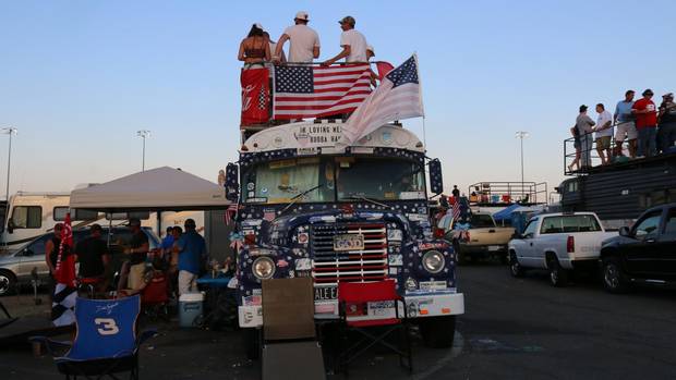 Fans atop a school bus take in the racing as the sun sets during the Coca-Cola 600 at Charlotte Motor Speedway.