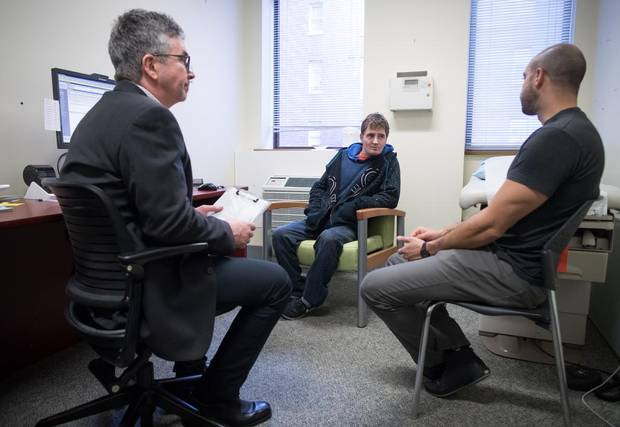 Dr. Mark McLean, left, and addictions registered nurse Sherif Amara, right, talk with patient Daniel Lagrois at St. Paul's Hospital, in Vancouver.