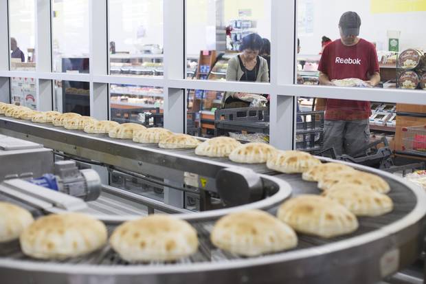 Customers hold packages of pitas as fresh pitas are baked at Adonis grocery store in Scarborough, Ont. on Saturday, July 29, 2017.