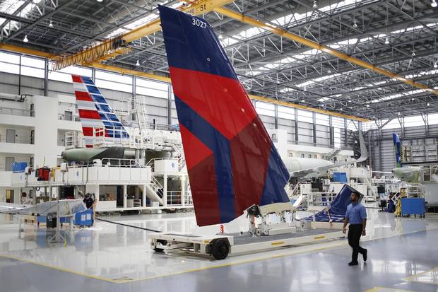 Employees walk past an Airbus SE A321 vertical stabilizer with a livery for Delta Air Lines Inc. on the production floor of the Airbus Final Assembly Line facility in Mobile, Alabama, U.S., on Wednesday, July 19, 2017.