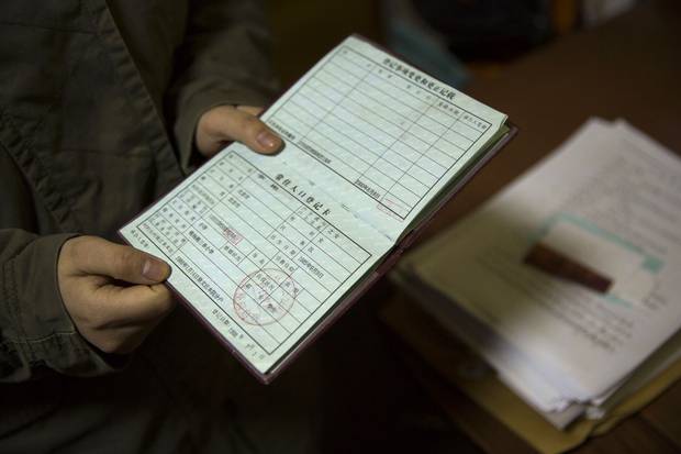 Li Xue, 21, who does not have hukou household registration documents, shows journalists her mother’s hukou in the bedroom they share in Beijing on March 10, 2015. The documents decide what services Chinese people can access, from home-ownership rights to public school enrolment, based on their families’ place of origin.