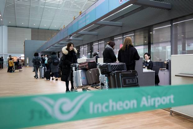Passengers stand at a Korean Air Lines check-in counter at Incheon International Airport.
