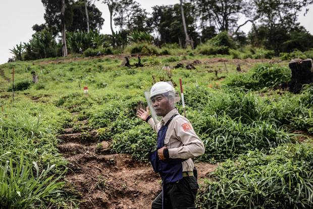 Choem Bo, HALO’s supervisor in Pailin province, prepares to enter a minefield. The crudely made steps cut into the side of the hill are the only safe place to walk; the red and white sticks mark land that has not been cleared.