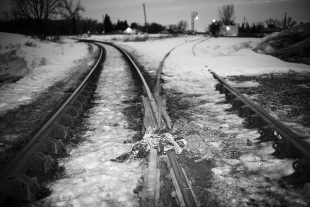 Abandoned clothing lies along the train tracks.