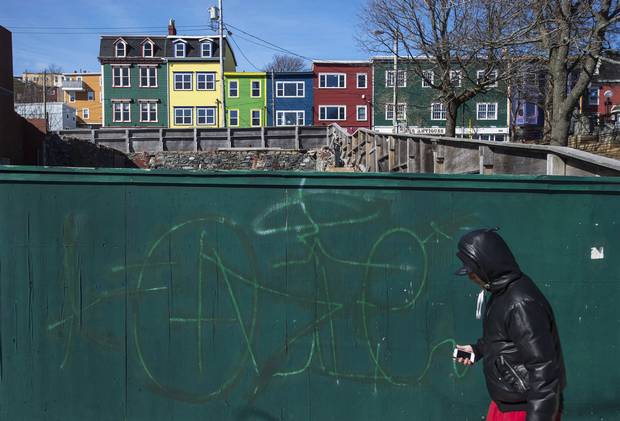 A man walks past a boarded-up construction site on Water Street in downtown St. John's.