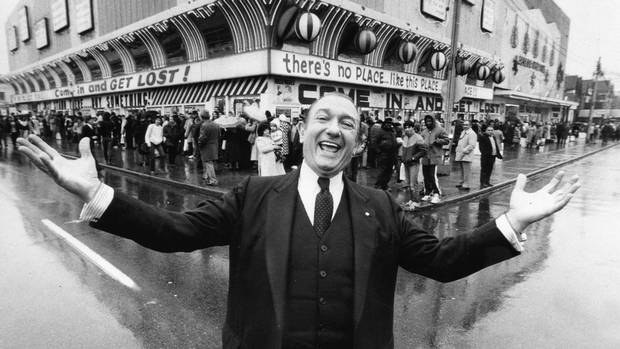 Entrepeneur Ed Mirvish throws his arms wide on Dec. 5, 1983 as hundreds of customers line up at his discount store on Bloor Street West for watches at five cents each.