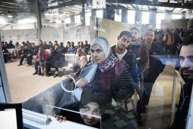 Syrian refugees line up for their UNHCR interview, right, or wait for their final interview with Canadian authorities, left, in Amman, Jordan.