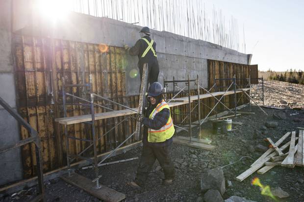 Travis Isadore, foreground, who has lived in the Paqtnkek reserve for 22 years, works on the highway interchange.