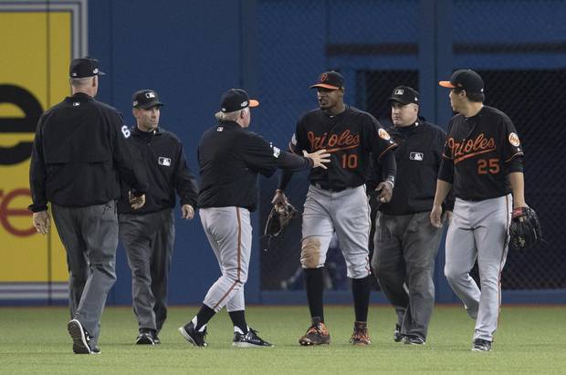 Umpires Ted Barrett, left to right, David Rackley, Baltimore Orioles manager Buck Showalter, Orioles' Adam Jones, umpire Eric Cooper and Orioles' Hyun Soo Kim talk after a beer was thrown onto the field during play following seventh inning on Tuesday.