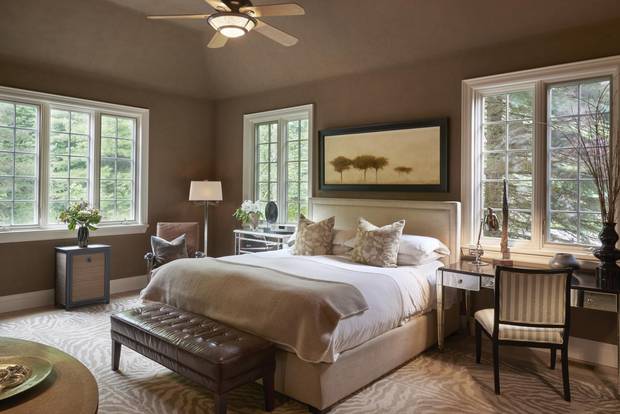 The master bedroom has large windows that peer onto the surrounding lush lot.