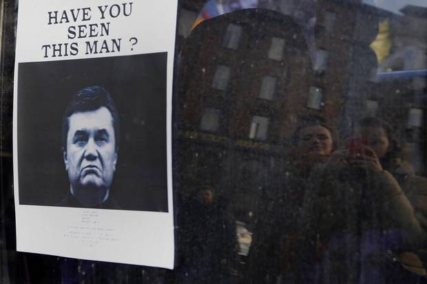 Ukrainians look at a “wanted” notice for fugitive Ukrainian president Victor Yanukovych in Kiev on Feb. 24, 2014.