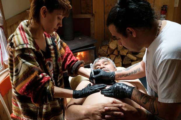 Cast member Russell Davis gets a traditional tattoo by artist Cory Bulpitt (right).
