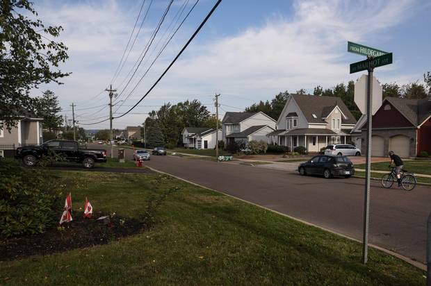 Three small Canadian flags remain in front of a brick monument marking the entrance to Rosemont park.
