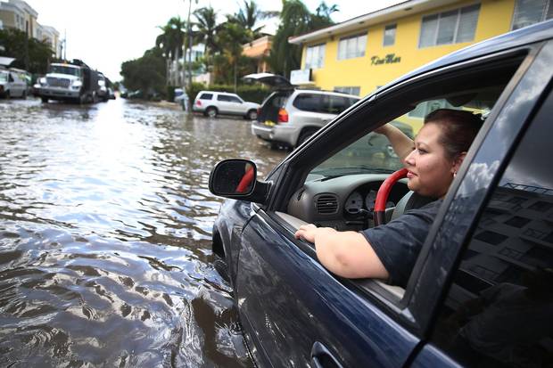 Sandy Garcia sits in her vehicle in Fort Lauderdale, Fla., that was stuck in a flooded street on Sept. 30, 2015.